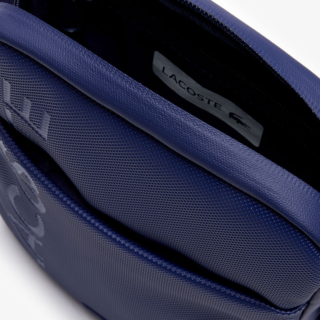 حقيبة صغيرة مسطحة بسحاب للرجال مزدانة بشعار العلامة التجارية من مجموعة L.12.12 حقيبة صغيرة مسطحة بسحاب للرجال مزدانة بشعار العلامة التجارية من مجموعة L.12.12